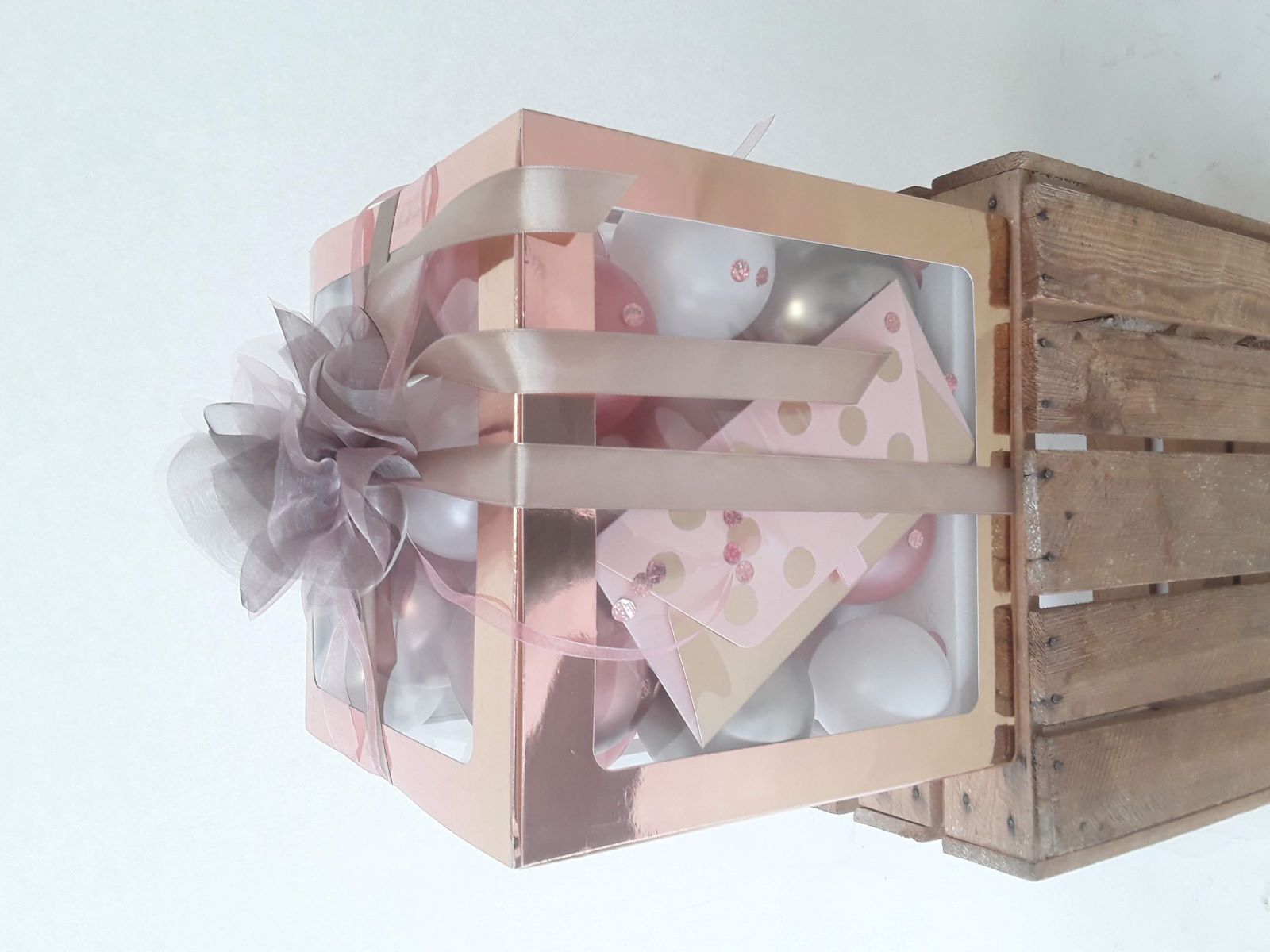 Ballonbox mit metallischer roséfarbener Hülle, gefüllt mit Luftballons in Rosé, Weiß und Silber, Konfetti und 18er-Aufdruck Ballon.