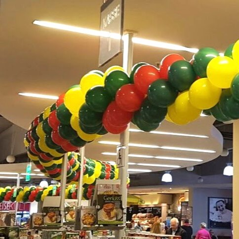 rot-gelb-grüne Ballongirlande über dem Ausgang mit Kassen eines Supermarktes