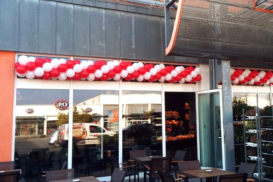 rot-weiße Ballongirlande über dem Eingang einer Bäckerei an der Außenfassade