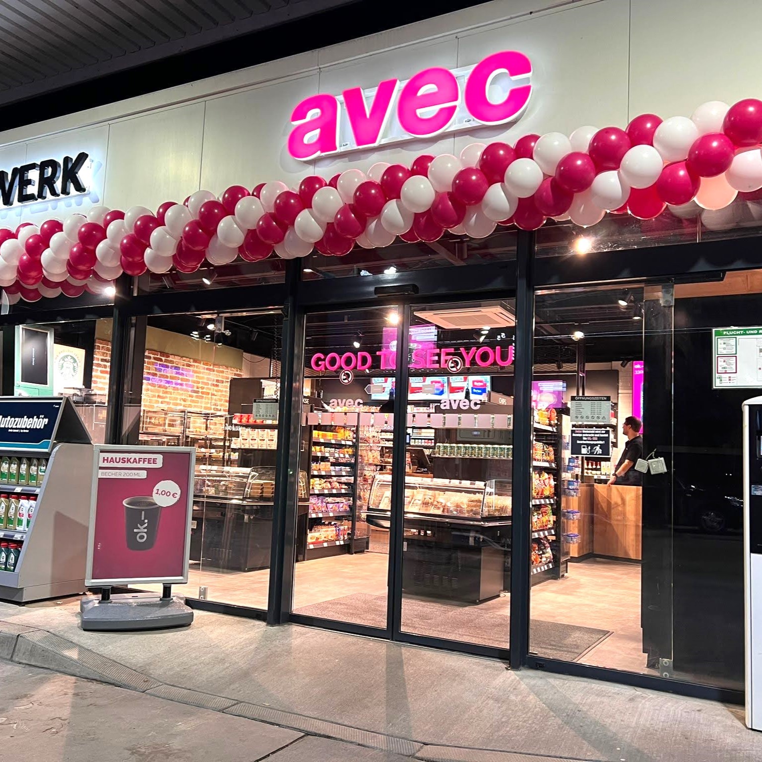 weiß-pinke Ballongirlande unter avec Schild über dem Ladeneingang