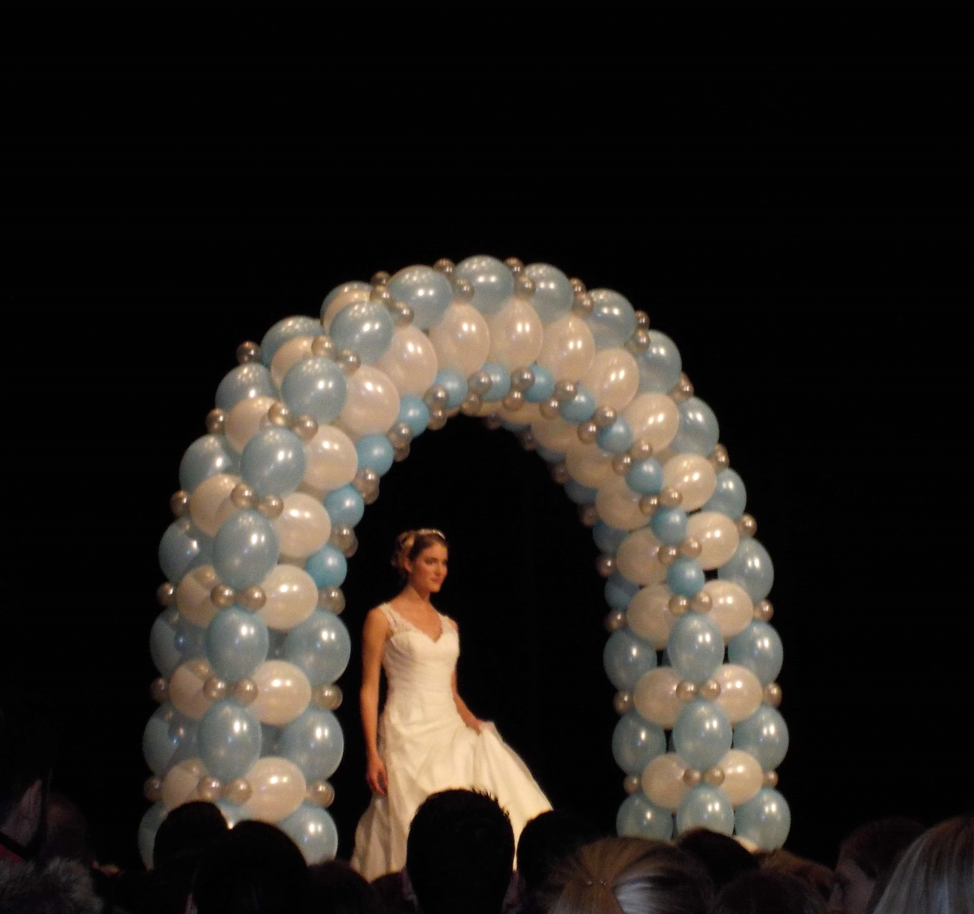 Ballonbogen in weiß und hellblau auf einer Bühne mit Model in weißem Kleid