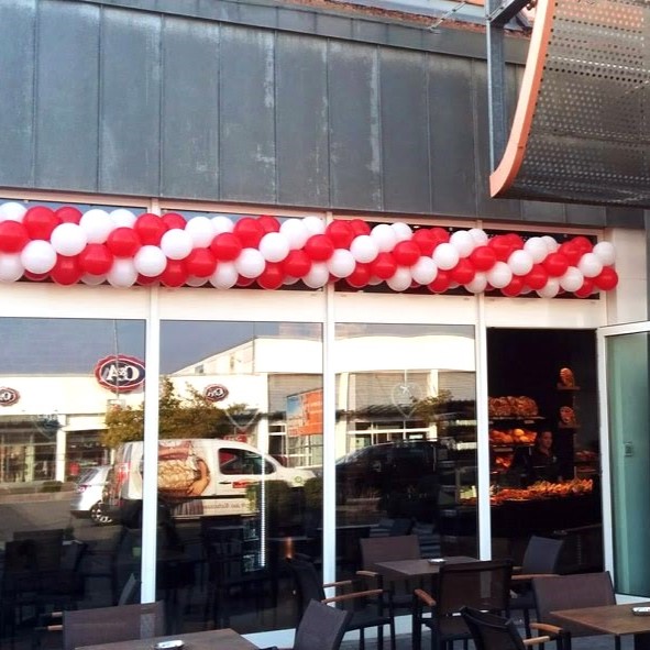 rot-weiße Ballongirlande über dem Eingang einer Bäckerei an der Außenfassade