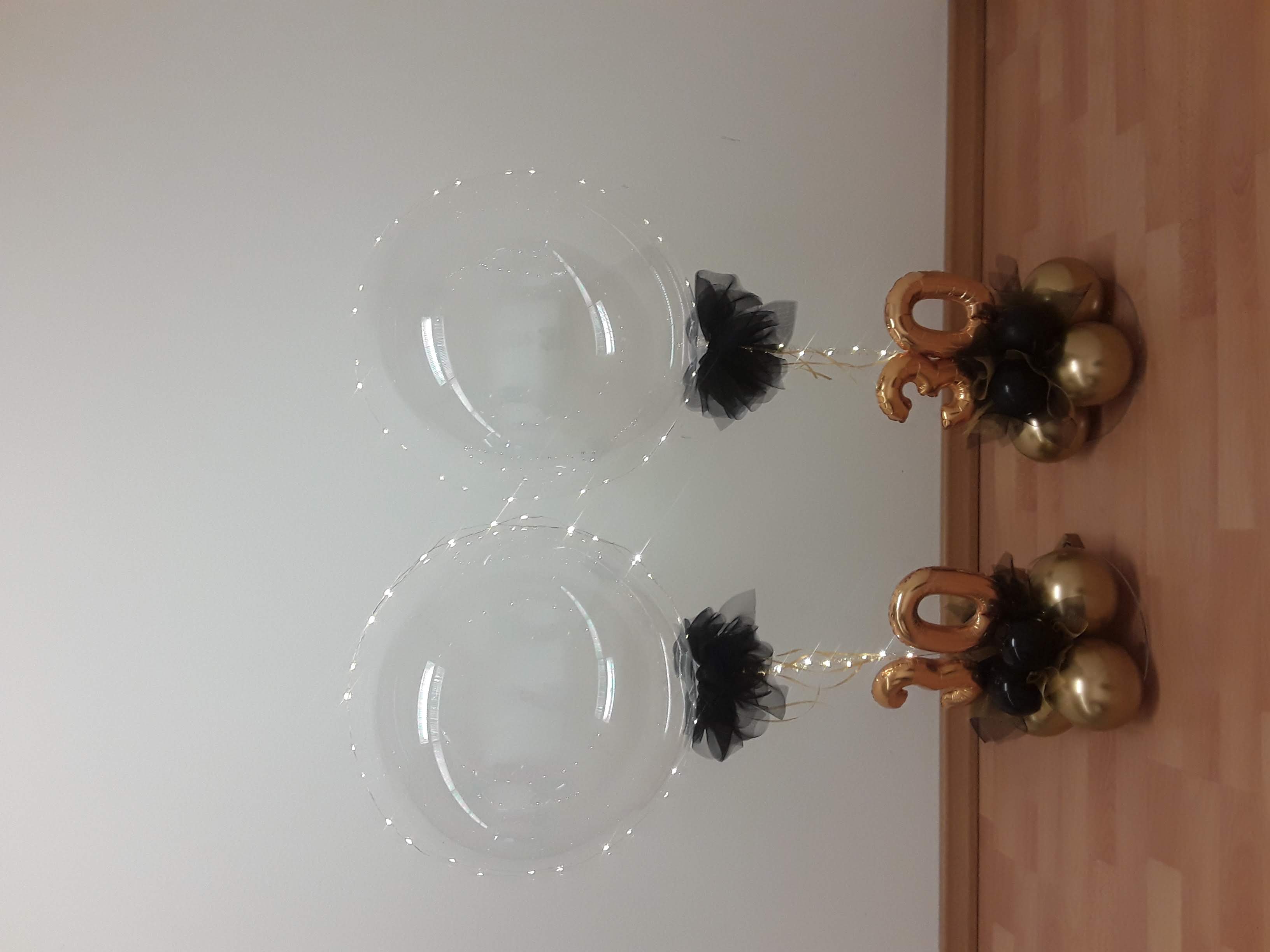 Zwei Tischständer mit je ransparenter Ballon mit Lichterkette, schwarze Schleife, goldene 30 auf Ballonbasis